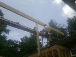 Carpenter setting a ridge beam over a new addition frame — Ice Dam Removal by Roofing Brothers in Contoocook
