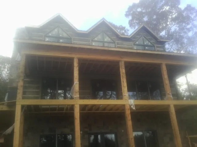 Dormers and porch framing on a large log home under construction — Roof Coating work by our crew in Contoocook