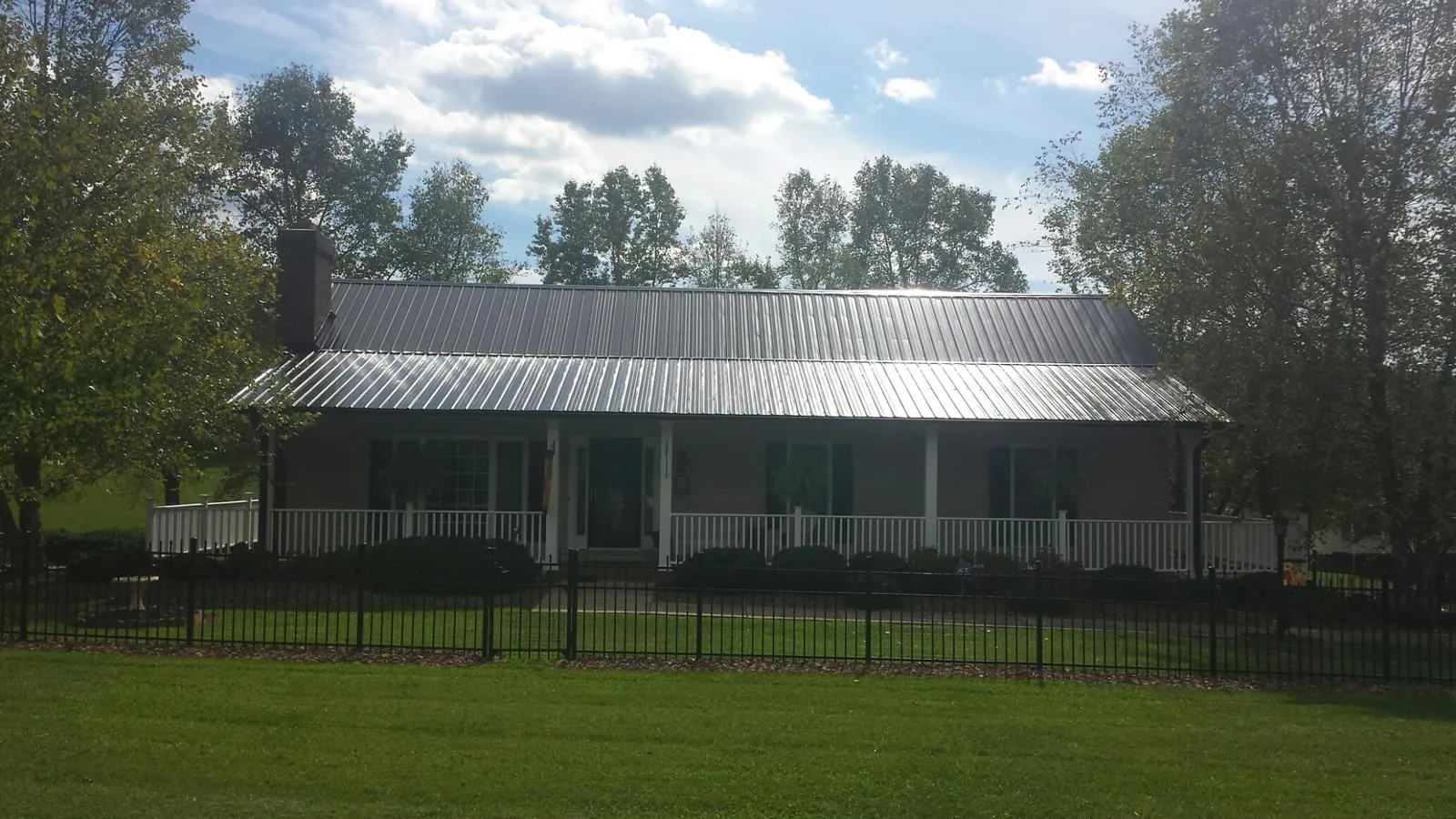 Gray metal roof on a brick ranch with a full width front porch — Gutter Guard Installation work by our crew in Contoocook