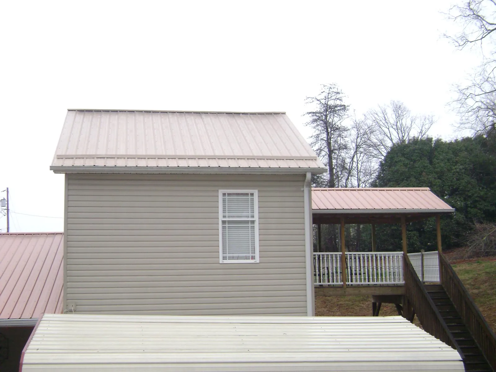 Tan metal roofs on a two story addition and attached porch, from a Roof Replacement job in Contoocook