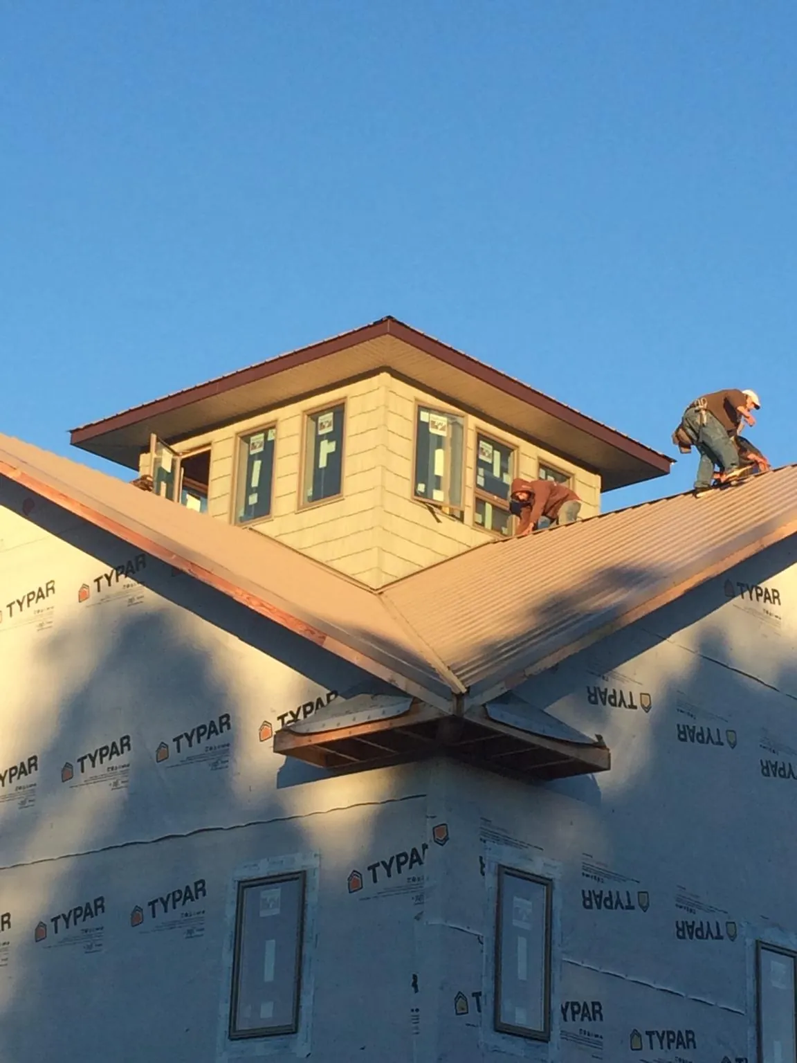 Roofers working around a rooftop cupola on a new metal roof at sunset — Roof Waterproofing in Contoocook by Roofing Brothers